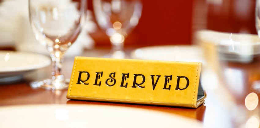 closeup of yellow reserved sign on a table top at a restaurant. soft focus with red background