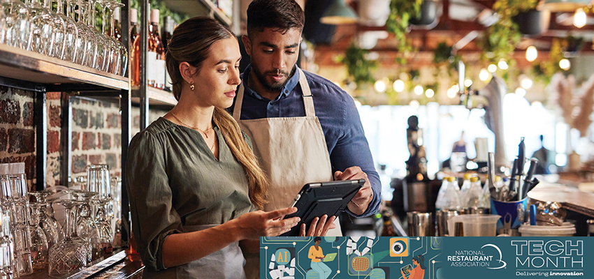 Two employees at a restaurant bar looking at an iPad