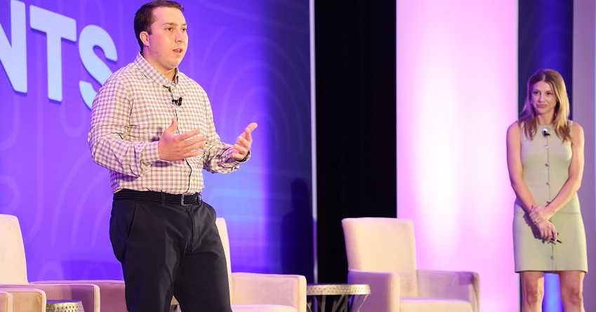 Kris Linney, left, and Devon Roscoe speaking on stage at MEG 2025 in front of purple backdrop