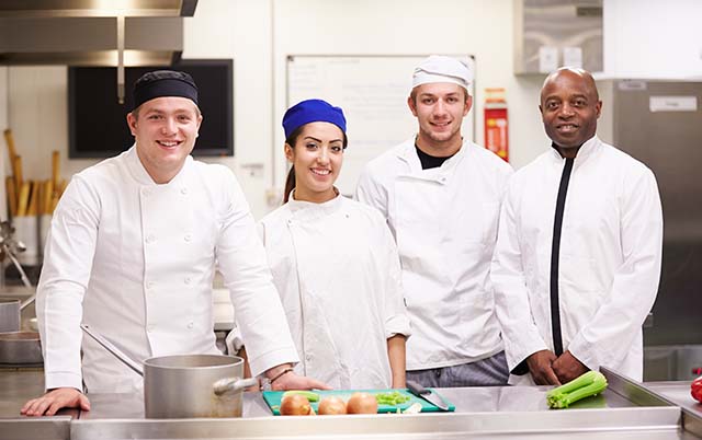 Four workers cooking in a restaurant kitchen - Restaurant Industry Job Titles