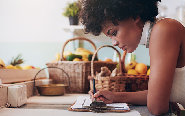 Woman writing on clipboard in front of baskets - Learning Center
